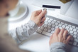 © Oleksandr - Hands of a woman holding a credit card and using a computer for online purchases.