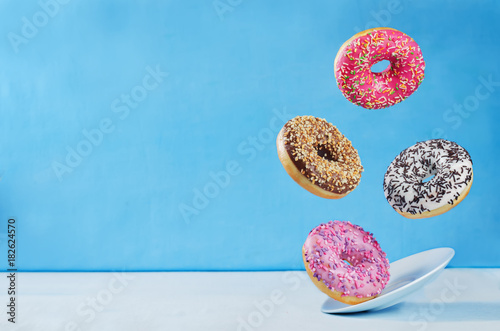 Fotografía Flying multicolored donuts with plate