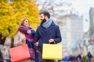 Beautiful young loving couple carrying bags and enjoying together holiday shopping