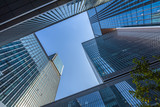 Fototapeta Paryż - Bottom view of modern skyscrapers in business district against blue sky.
