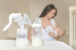© evso - Manual breast pump and bottle with breast milk on the background of mother holding in her hands and breastfeeding baby. Maternity and baby care.