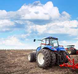 Fototapete - Agricultural machinery cultivates the field
