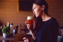 Young Brunette Drinking A Beer In A Restaurant