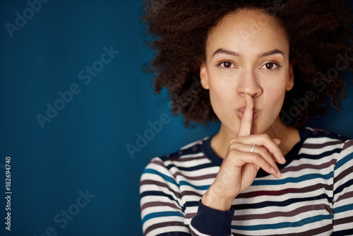 Foto Mischrassefrau, die eine Nachahmung für Ruhe bei der Stellung vor blauer Wand ma