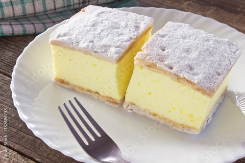 Fotografie, Obraz Cream pie with layers of puff pastry in plate on wooden table