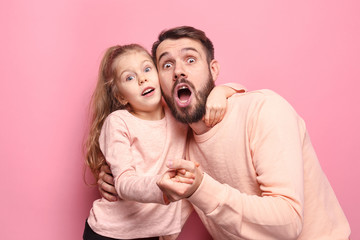 Wall Mural - Surprised young family looking at camera on pink