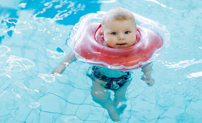 Wall Mural - Cute little baby child learning to swim with swimming ring in an indoor pool