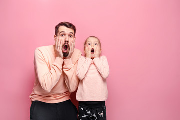 Wall Mural - Surprised young family looking at camera on pink