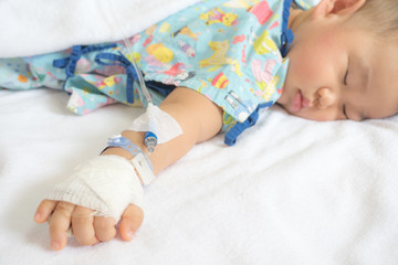 Wall Mural - Closeup of hands of a little Boy attaching intravenous tube to patient's hand in hospital bed.