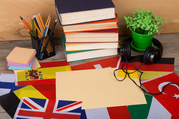Fototapete - Learning languages concept - blank paper, flags, books, headphones, pencils on wooden background