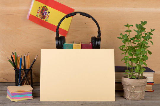 Concept of learning the spanish language - blank paper, flag of the Spain, books, headphones, pencils on wooden background