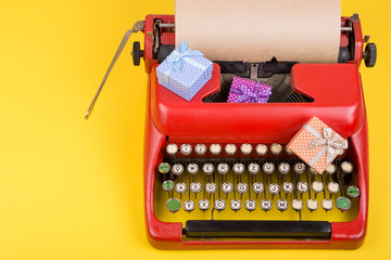 Poster - Holidays concept - red typewriter with blank craft paper, gift boxes on yellow background