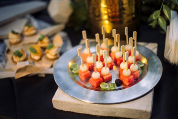 Kanape from watermelon, laid out on a silver plate.