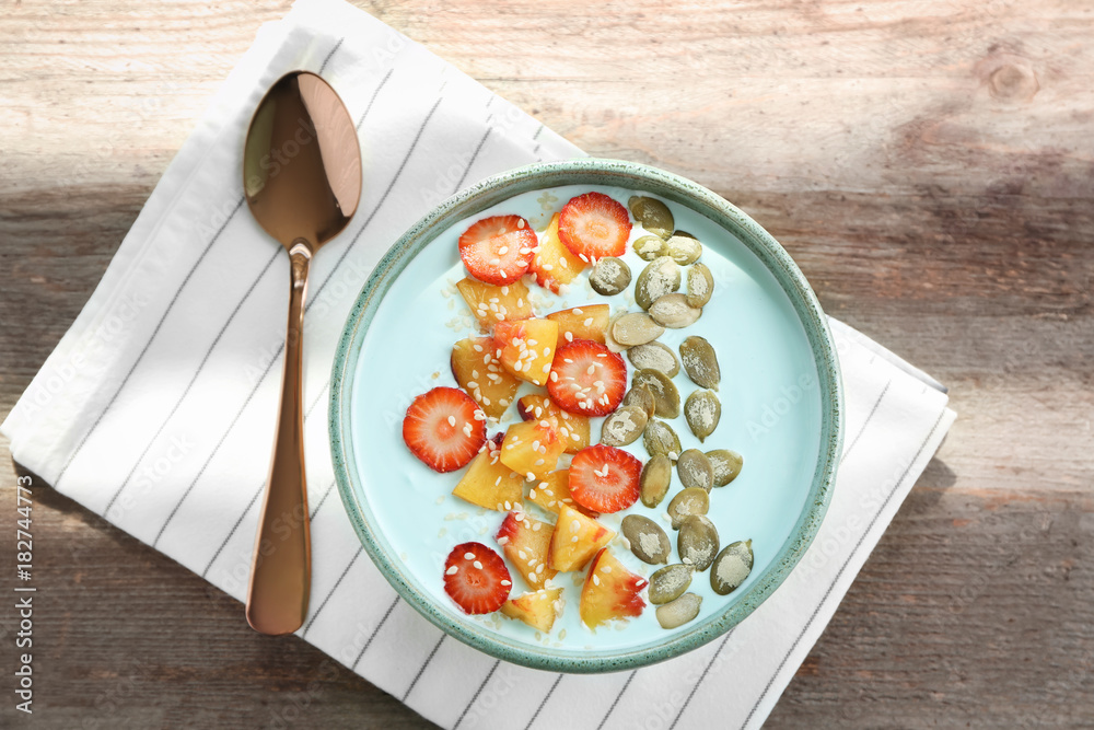 Bowl with yummy spirulina smoothie and bottle of drink on wooden table. Healthy vegan food concept
