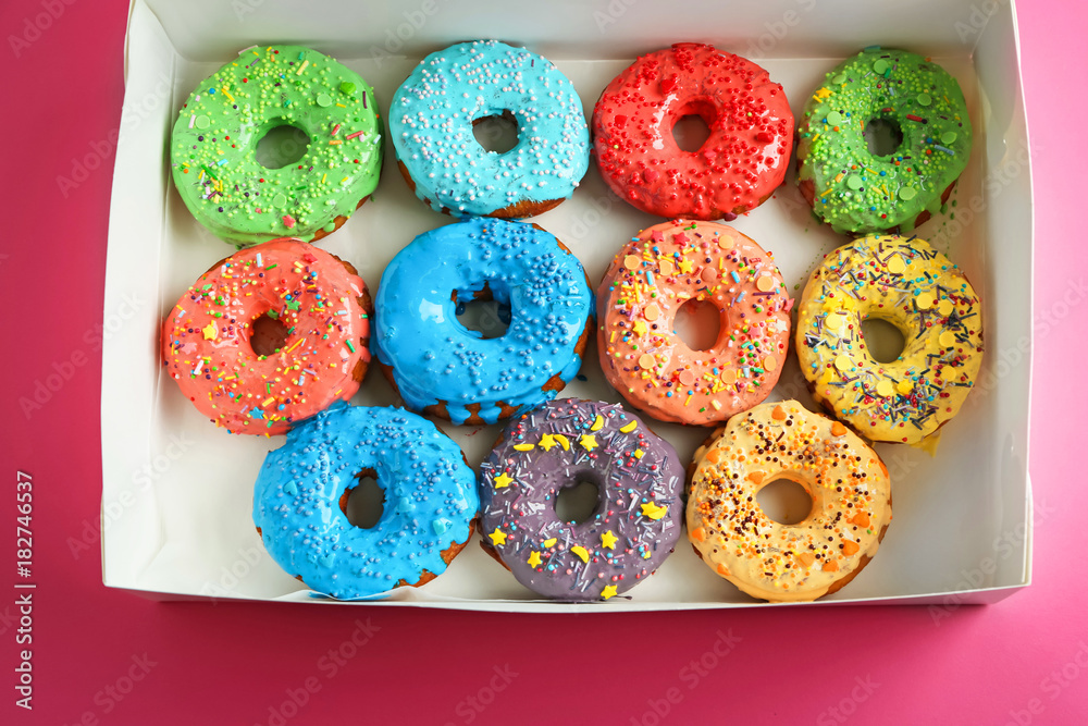 Tasty glazed donuts in box on color background