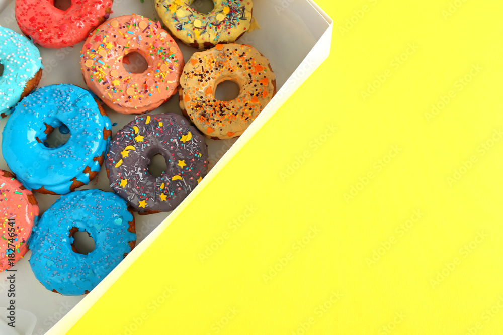 Tasty glazed donuts in box on color background
