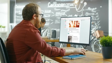 Poster - Creative Office Worker Browsing Social Network Pages, He Scrolls Through His Wall on a Personal Computer. In the Background Stylish Creative Agency Room. Shot on RED EPIC-W 8K Helium Cinema Camera.
