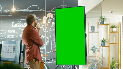 Poster - Male Developer Looks at Interactive Whiteboard with Mock-up Green Screen. He Smooths His Beard Thinking on a Problem Solution. Shot on RED EPIC-W 8K Helium Cinema Camera.