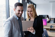 © NDABCREATIVITY - Attractive business couple using tablet in modern office