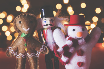 Wall Mural - Festive snowman, nutcracker and gingerbread man decorations against a bokeh fairy light background