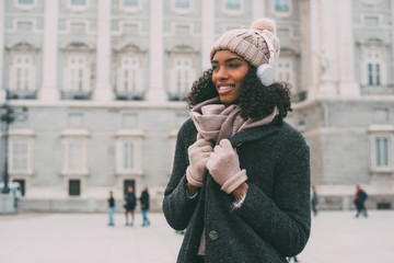 Young black woman listening to music and dancing on the mobile phone near the royal palace in winter  .