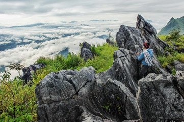 Wall Mural - Tourist take a picture by mobile on Mountain view with landmark of big stone at Doi pha tang number 103 in chiangrai tourist attraction in thailand
