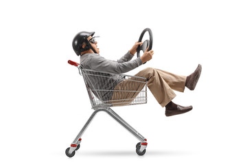 Wall Mural - Mature man with a helmet and a steering wheel riding inside a shopping cart