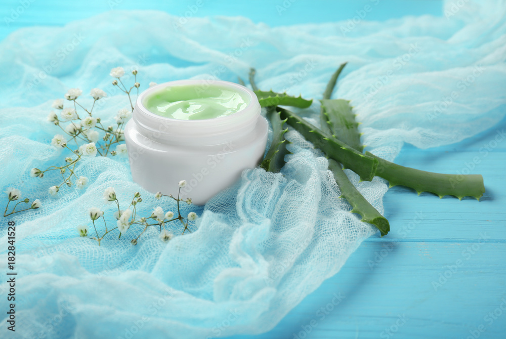 Jar with body cream on color wooden background