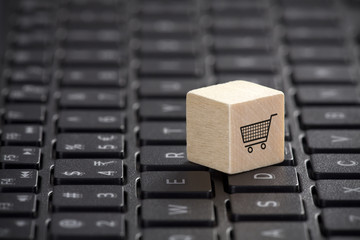 Fototapete - Wooden block with shopping cart graphic on laptop keyboard. Online shopping concept. 
