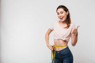 Wall Mural - Portrait of a slim satisfied woman holding measuring tape