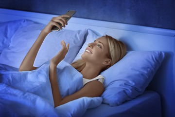 Sticker - Beautiful young woman with mobile phone in bed at night