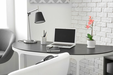 Comfortable workplace with laptop on table in office