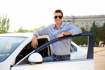 Young man standing near car on city street