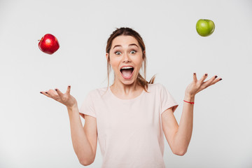 Portrait of a happy girl throwing apples in the air