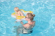 © serejkakovalev - young mother with one year kid swim in blue pool and having good time