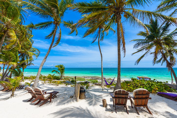 Wall Mural - Chairs under the palm trees on paradise beach at tropical Resort. Riviera Maya - Caribbean coast at Tulum in Quintana Roo, Mexico