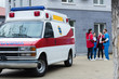 © LIGHTFIELD STUDIOS - Four ambulance doctors talking and standing near car
