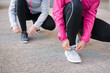 Close up of women lacing sport shoes and getting ready for urban running. Fitness workout and healthy lifestyle concept.