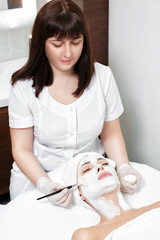 Wall Mural - beautician applies mask to the face of  woman 