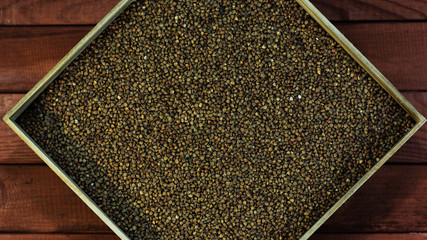 Poster - Buckwheat in a wooden box. Beautiful red wood table.