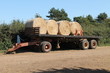 A Farm Flat Bed Trailer with Four Round Bales of Hay.