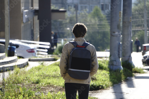 Fotografía A young boy wearing a cap with a backpack walking through the city