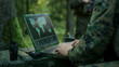 © Gorodenkoff - Military Operation in Action, Soldiers Using Military Grade Laptop Targeting Enemy with Satellite. In the Background Camouflaged Tent on the Forest.