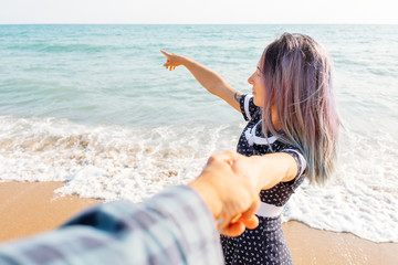 Poster - Woman holding man's hand and pointing at sea