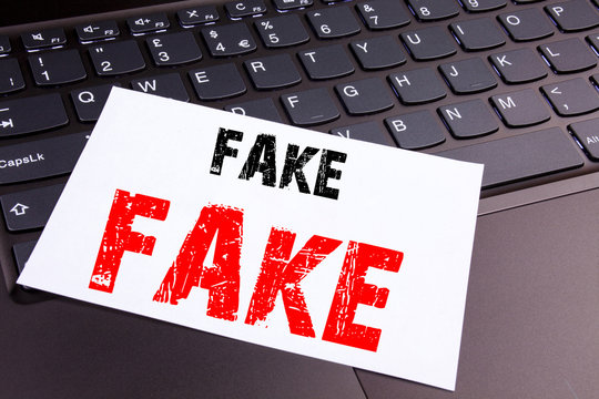 Writing Fake News text made in the office close-up on laptop computer keyboard. Business concept for Fake News Workshop on the black background with copy space