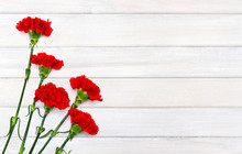 Bouquet Of Red Carnations (Dianthus Caryophyllus) On Background Of White Painted Wooden Planks With Space For Text. Top View, Flat Lay