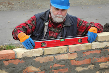 Wall Mural - Worker control brick wall using level tool, real people, no retouch