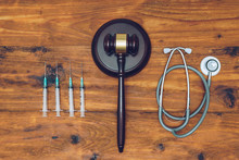 Syringes, Stethoscope And  Judge Gavel On Wooden Background.