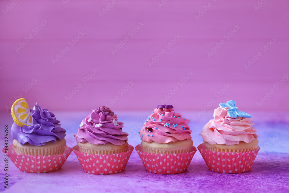 Tasty bright cupcakes on color background