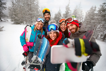 Wall Mural - smiling friends with ski on winter holidays - Skiers having fun on the snow